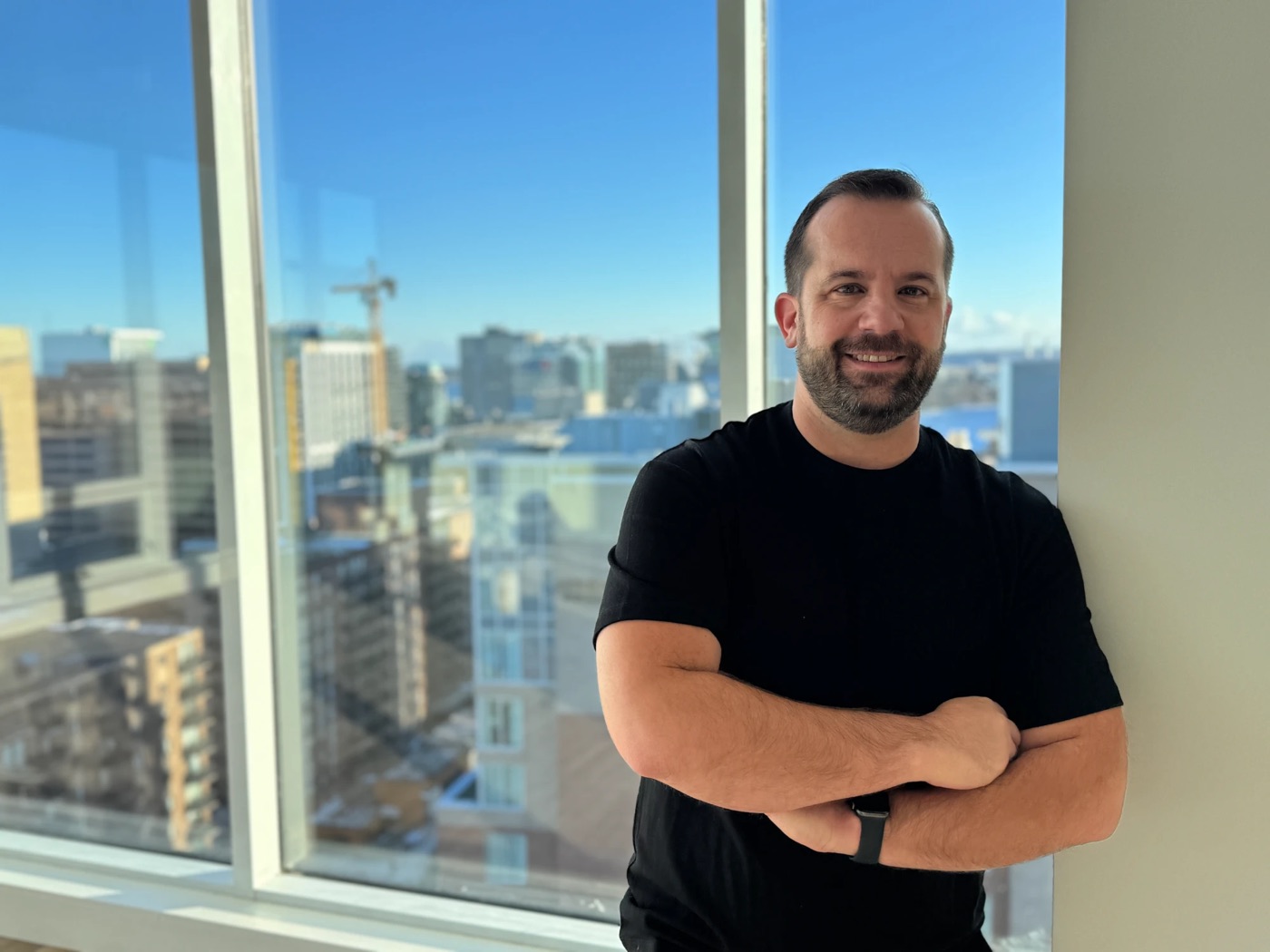 Ashley Frank, arms crossed, in front of a window overlooking the city